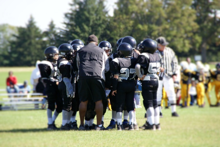 Youth huddle on a football field