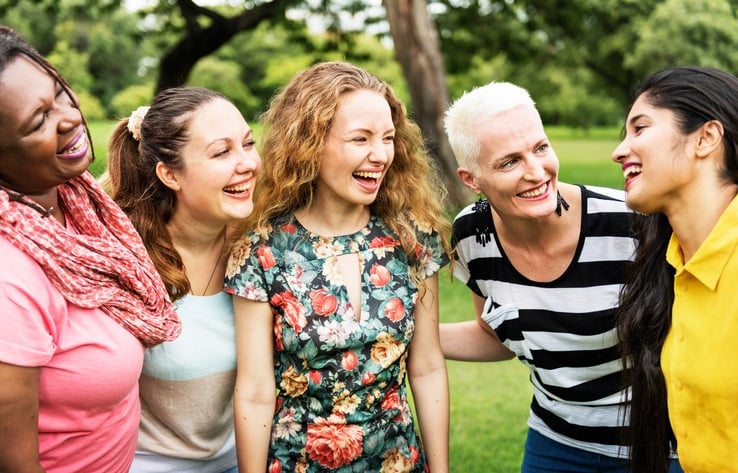 Group of five women laughing outdoors