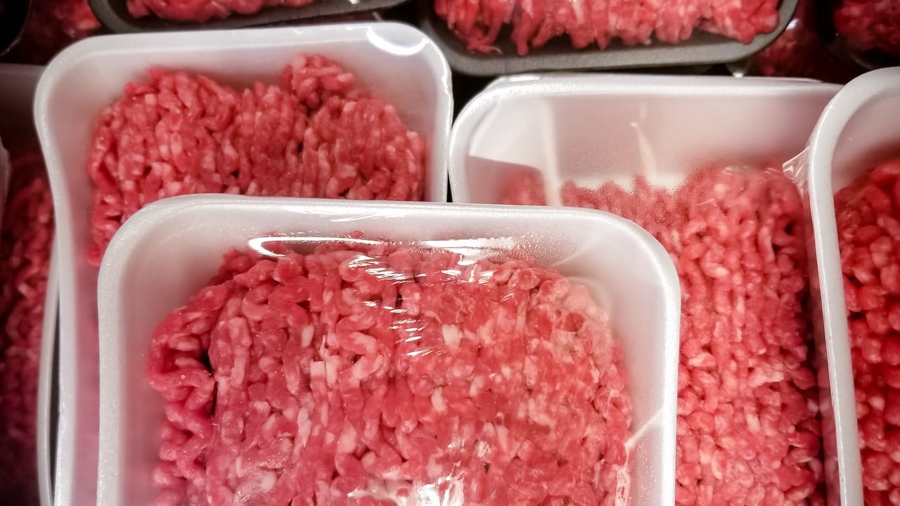 Packs of raw ground beef stacked up on top of each other. 
