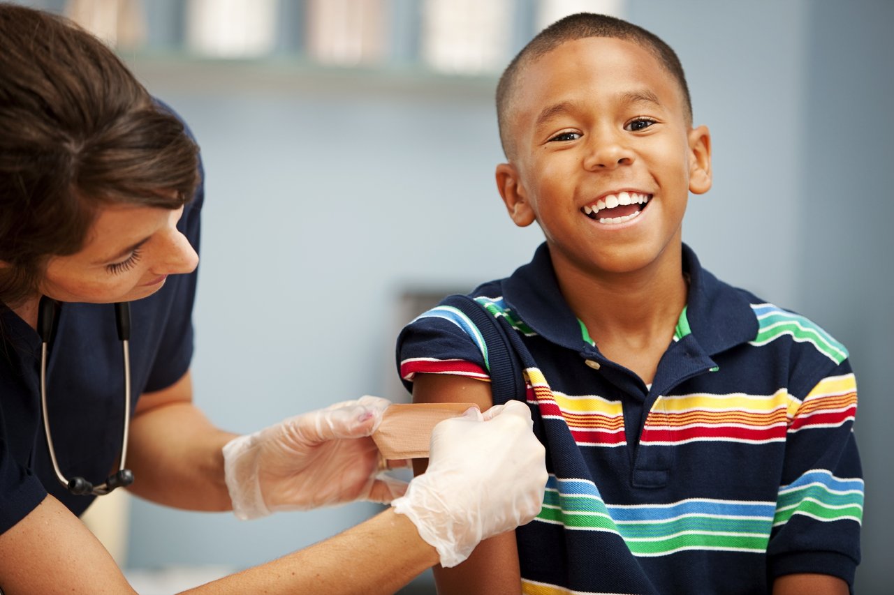 Little boy smiles while getting a bandaid after receiving his flu shot