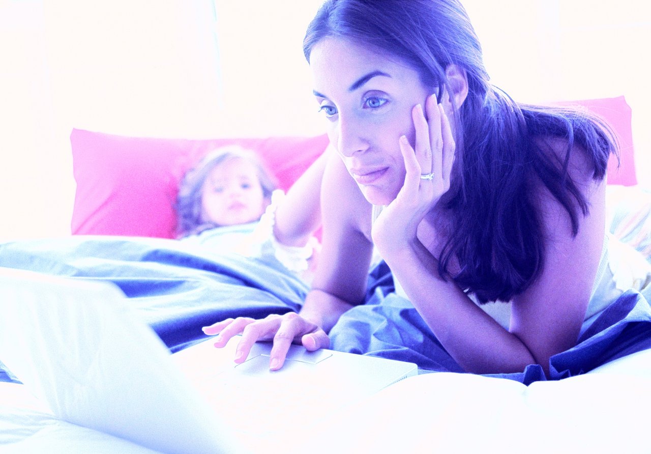 Young mom looking at computer with her child.